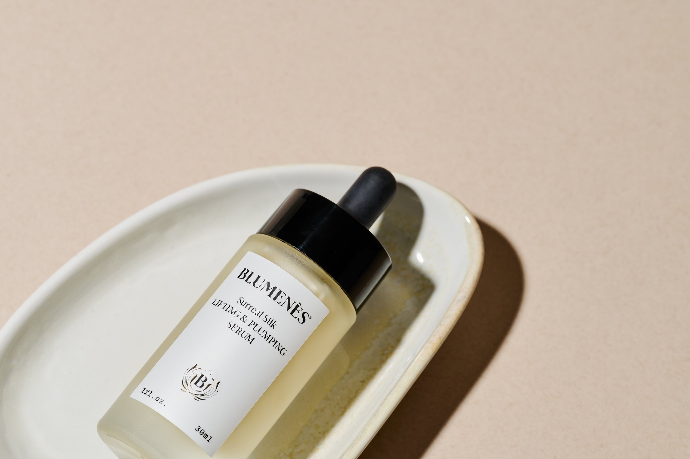 Blumenes skincare bottle on a beige plate with a beige background
